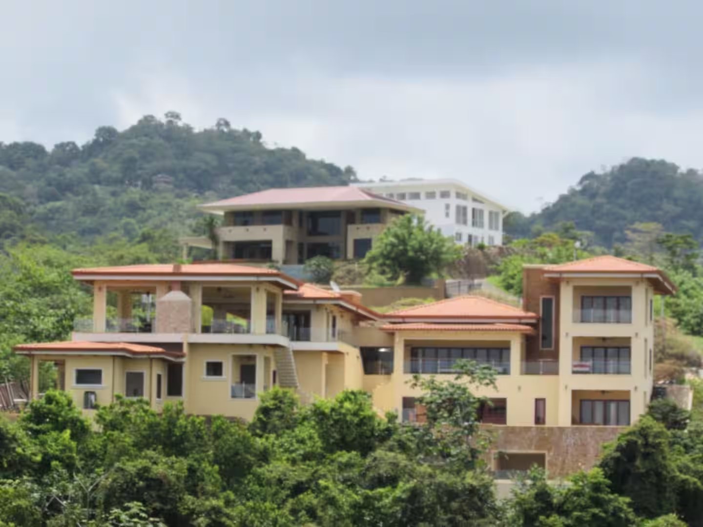 Orange-roofed multi-level homes on a lush green tropical hillside